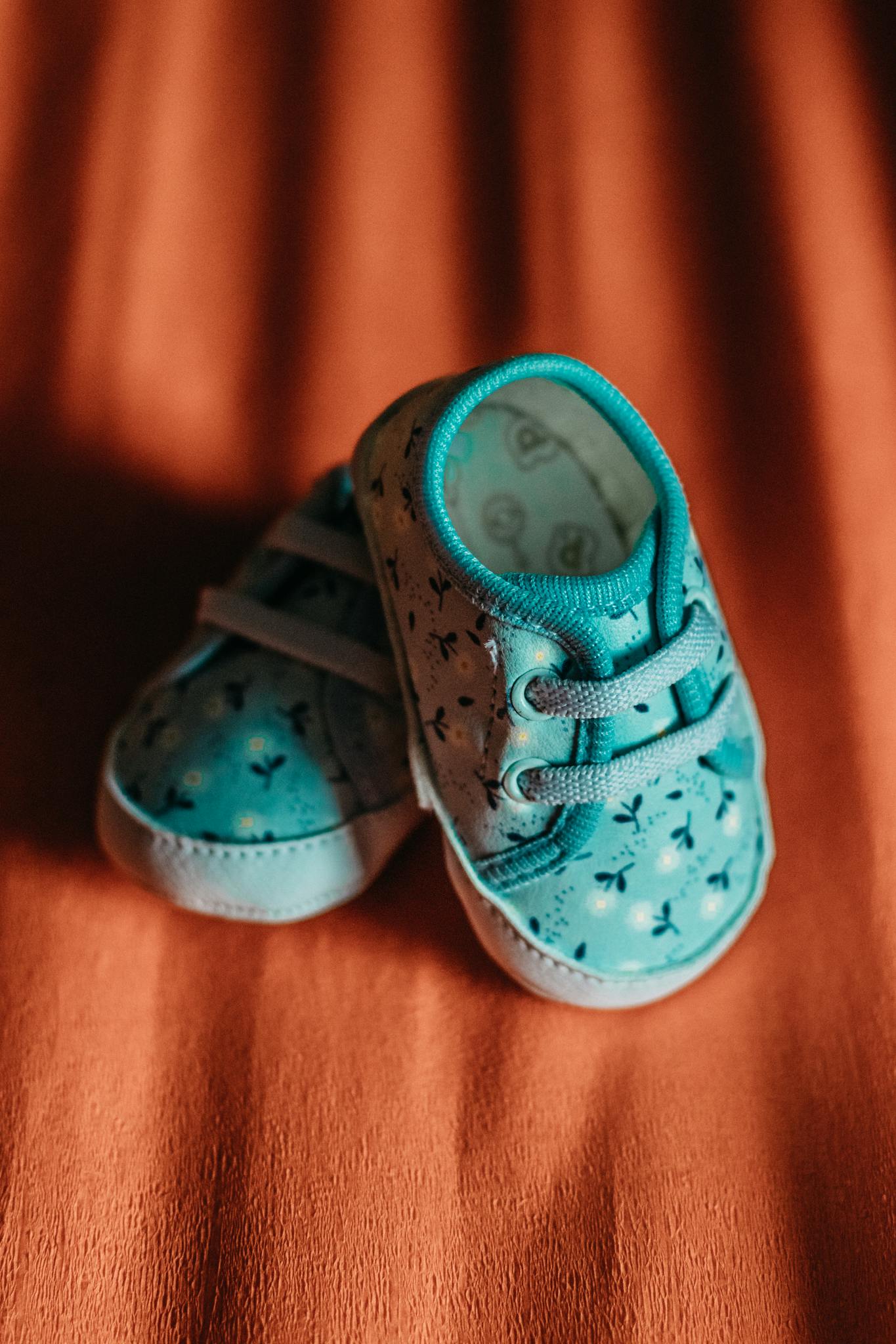 Close-up of cute blue baby shoes on soft orange fabric, enhancing their stylish design.